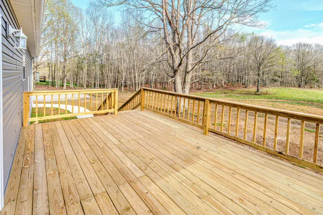 a view of deck with large trees and wooden fence