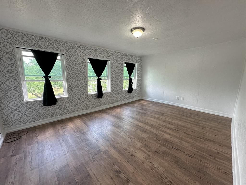 506 Northeast 3rd Street Hubbard, TX 76648 - Photo 15 of 17 an empty room with wooden floor and windows