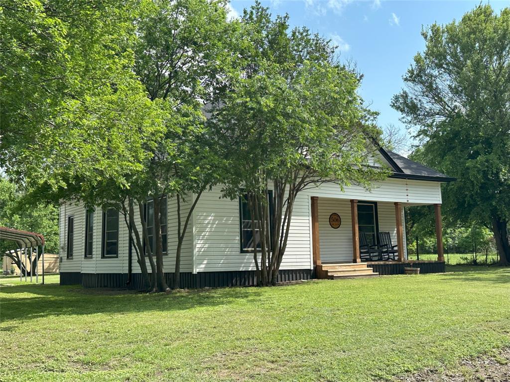 506 Northeast 3rd Street Hubbard, TX 76648 - Photo 2 of 17 a view of a white house with a big yard and large trees
