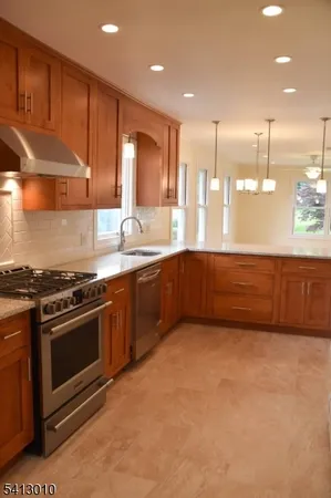 a kitchen with stainless steel appliances granite countertop a sink a stove and a refrigerator