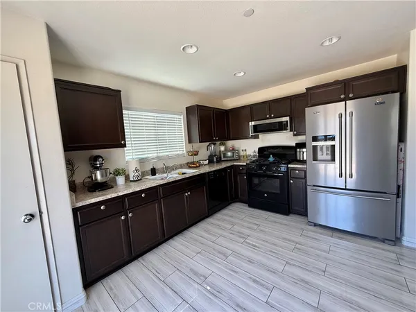 a kitchen with stainless steel appliances granite countertop a refrigerator a sink a stove top oven and wooden floors
