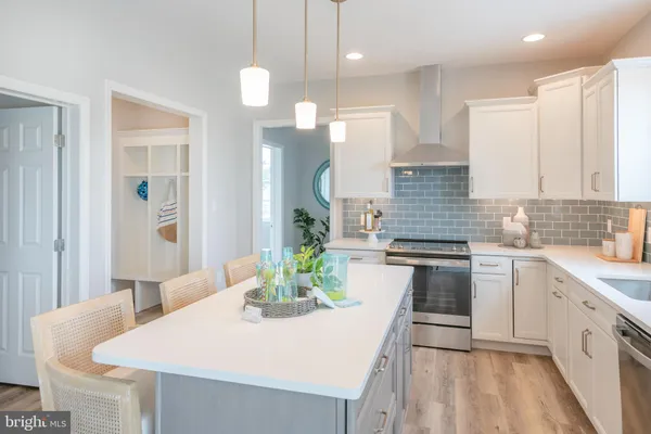 a kitchen with stainless steel appliances granite countertop a sink a stove a oven a dining table with chairs and white cabinets