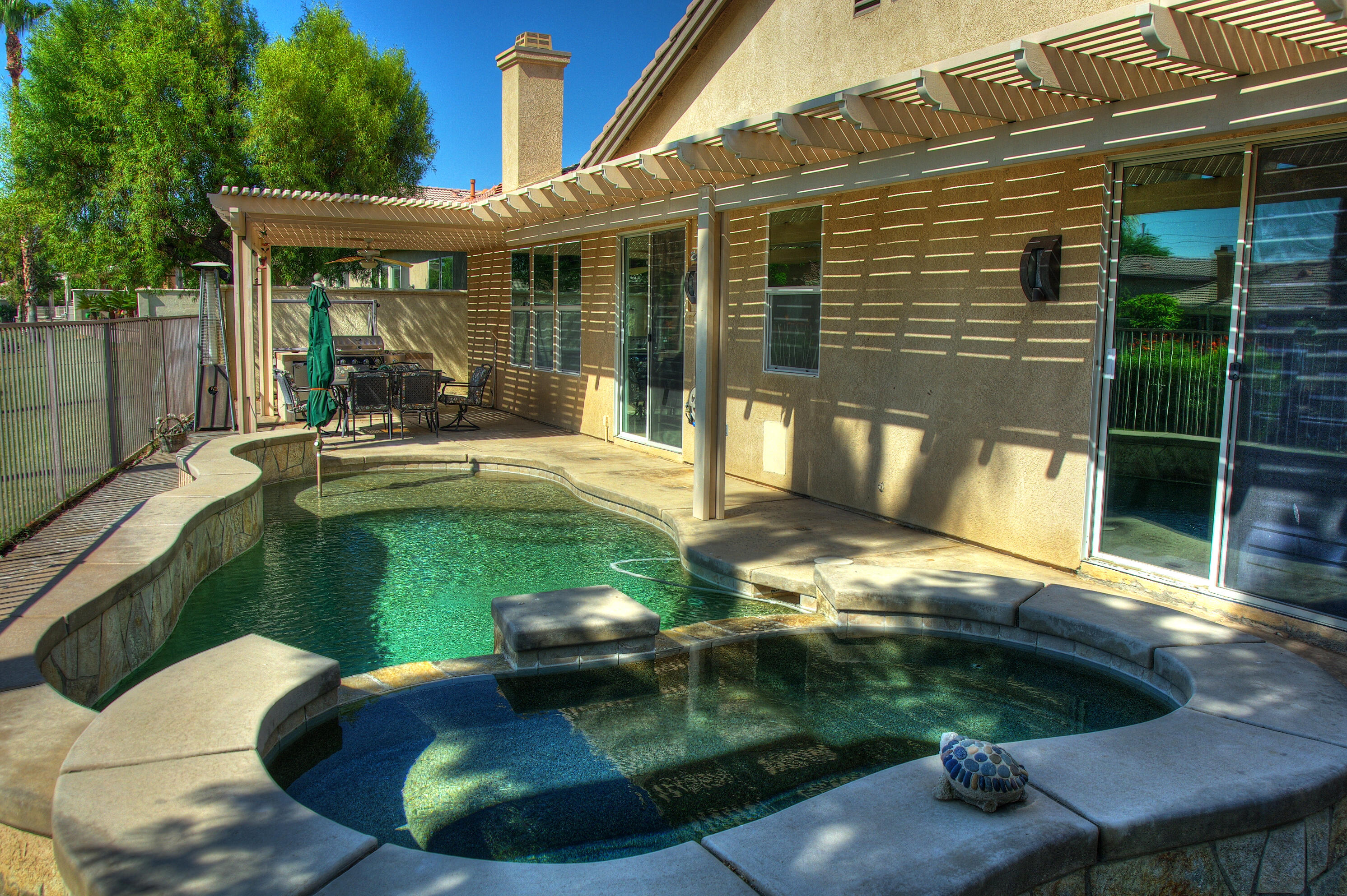 49714 Newman Circle Indio, CA 92201 - Photo 33 of 42 a view of a backyard with table and chairs potted plants and floor to ceiling window