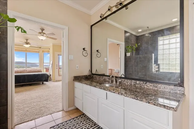 a en suite bathroom with a granite countertop sink and a mirror