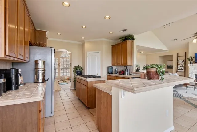 a room with stainless steel appliances kitchen island granite countertop a sink and cabinets