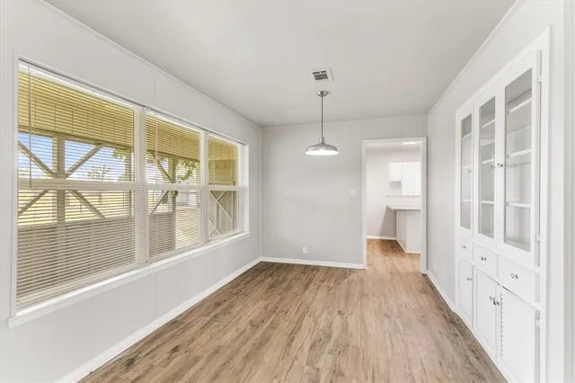 a view of an empty room with a window and wooden floor