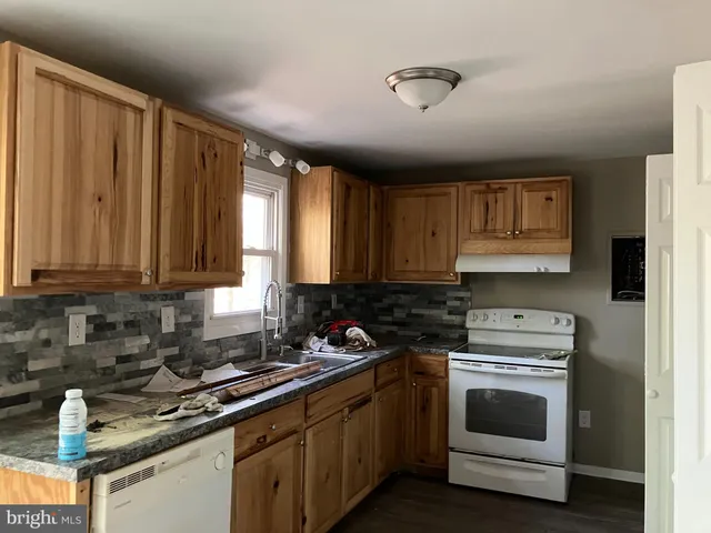 a kitchen with granite countertop a stove sink and cabinets