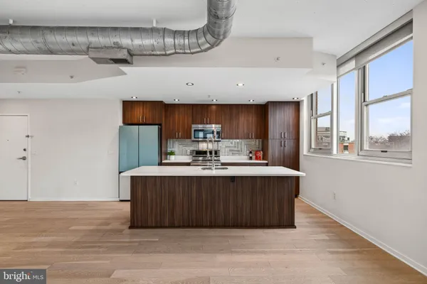 a view of kitchen with kitchen island stainless steel appliances wooden floor and window