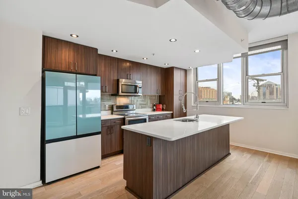 a large kitchen with kitchen island a large counter top space a sink stainless steel appliances and cabinets