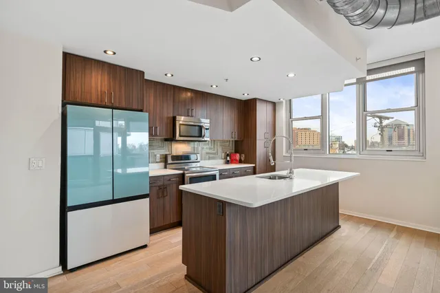 a kitchen with stainless steel appliances kitchen island wooden floors and living room view