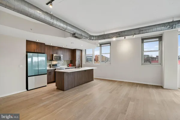 a kitchen with stainless steel appliances kitchen island wooden floors and living room view
