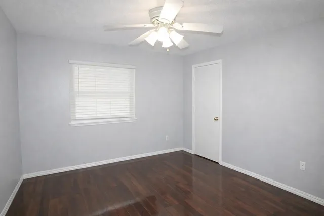 an empty room with chandelier fan and windows