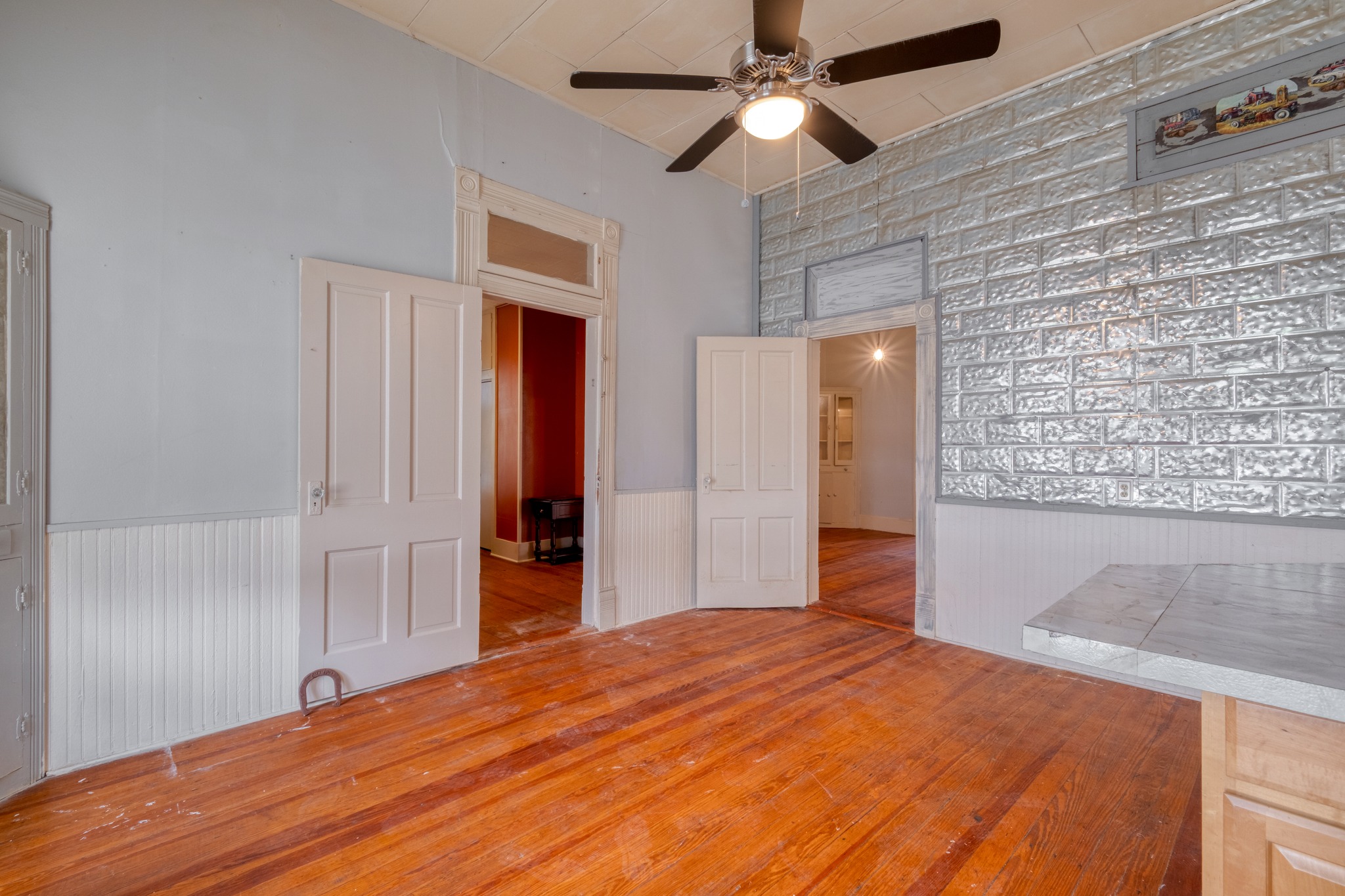 300 South Rio Grande Street Granger, TX 76530 - Photo 12 of 25 Unfurnished room with a wainscoted wall, hardwood / wood-style flooring, a ceiling fan, and a high ceiling