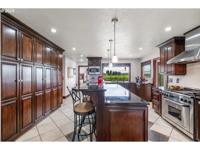 a kitchen with stainless steel appliances granite countertop a refrigerator a stove and a sink with wooden floor
