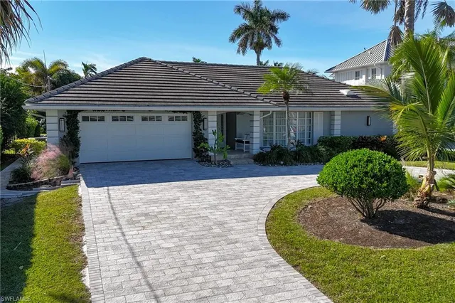 a front view of a house with a yard and potted plants
