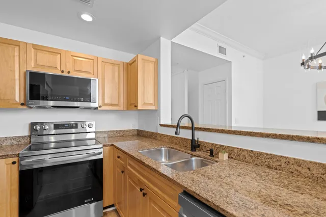 a kitchen with granite countertop a sink and a stove top oven with wooden floor
