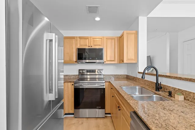 a kitchen with stainless steel appliances granite countertop a sink stove and refrigerator