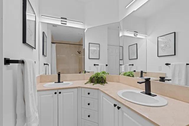 a bathroom with a granite countertop double vanity sink mirror and shower
