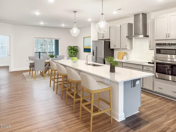 a large kitchen with stainless steel appliances a large island oven a sink dishwasher and a stove with wooden floor