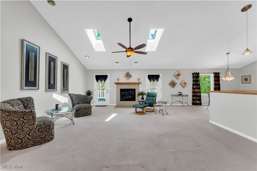 8651 State Road North Royalton, OH 44133 - Photo 8 of 33 Carpeted living area with lofted ceiling, ceiling fan, a tile fireplace, and a skylight
