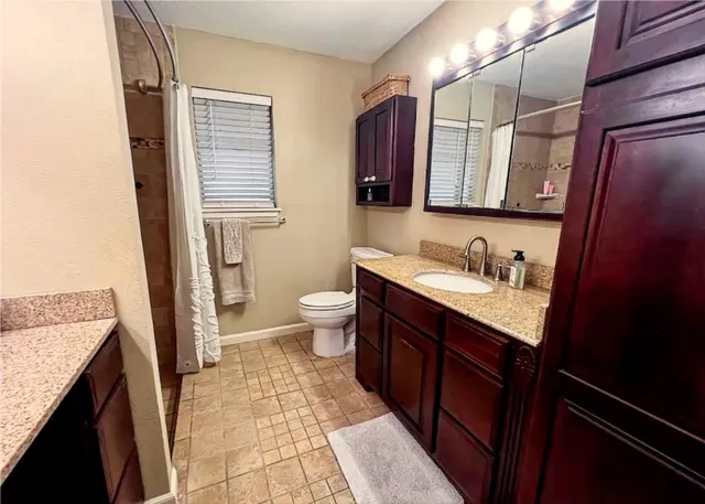 a bathroom with a granite countertop sink toilet and shower