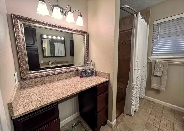 a bathroom with a granite countertop sink a mirror and a shower