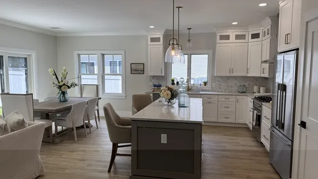 a kitchen with stainless steel appliances granite countertop a table chairs stove a sink dishwasher and a refrigerator