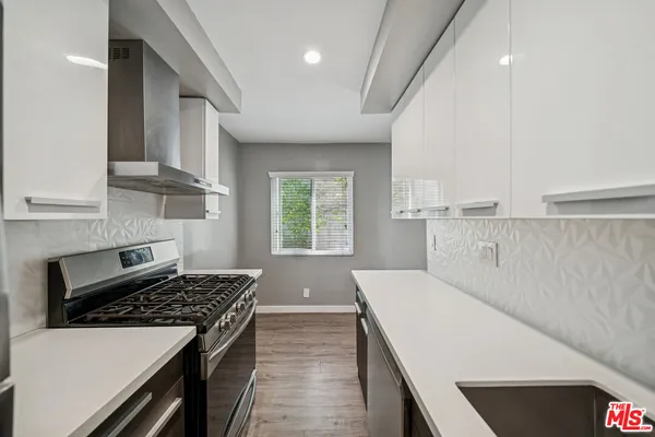 a kitchen with stainless steel appliances a white stove top oven a sink dishwasher and a refrigerator