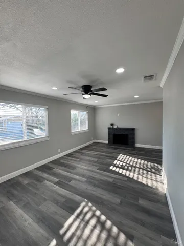 a view of empty room with wooden floor and kitchen