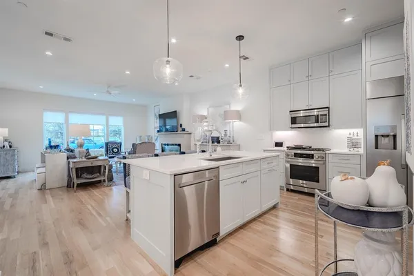 a kitchen with stainless steel appliances granite countertop a stove top oven a sink dishwasher a dining table and chairs with wooden floor