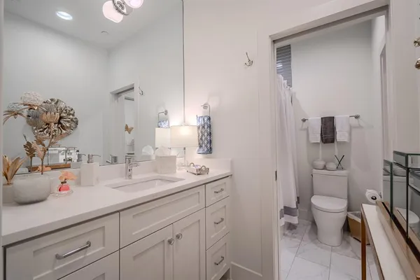 a spacious bathroom with a granite countertop sink a toilet and a mirror