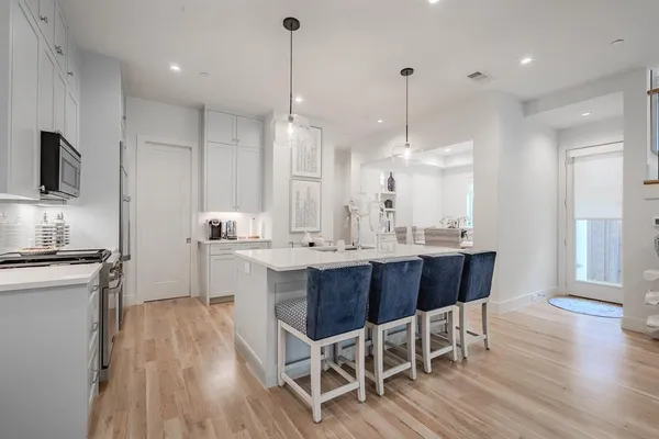 a kitchen with stainless steel appliances granite countertop wooden floors stove and white cabinets