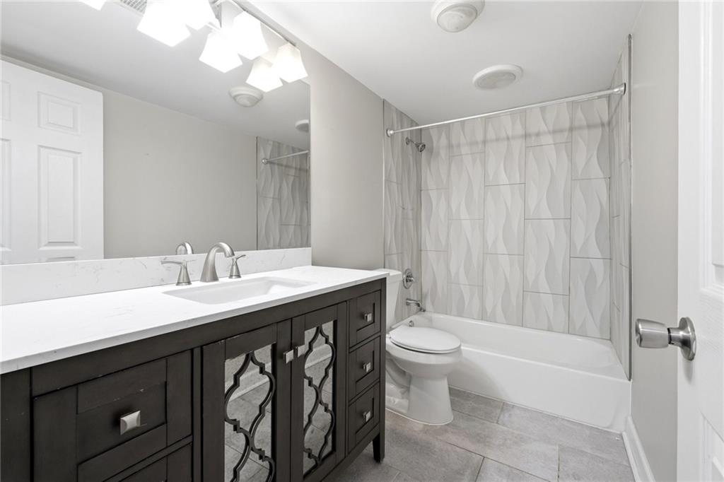 1150 Collier Road Northwest, Unit 4C Atlanta, GA 30318 - Photo 17 of 27 a bathroom with a sink a toilet a mirror a vanity and shower