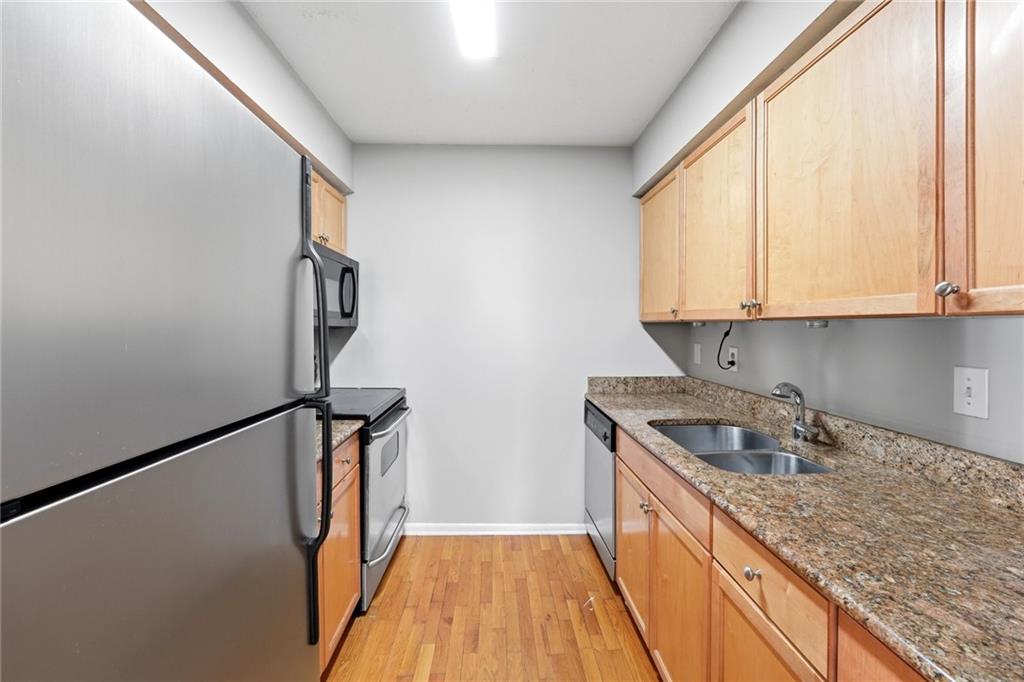 1150 Collier Road Northwest, Unit 4C Atlanta, GA 30318 - Photo 9 of 27 a kitchen with stainless steel appliances granite countertop a sink a stove and a refrigerator with wooden floor