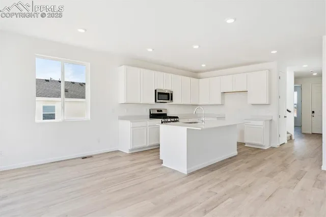 a kitchen with stainless steel appliances white cabinets and wooden floor