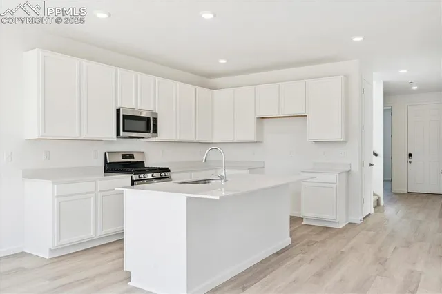 a kitchen with stainless steel appliances a sink stove top oven and white cabinets