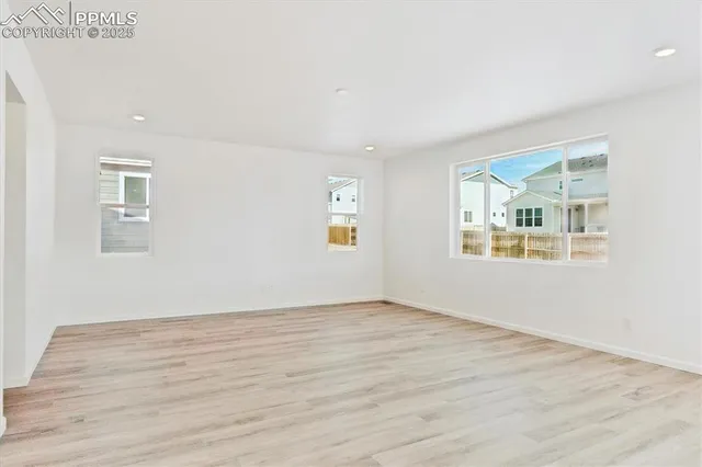 an empty room with wooden floor and windows
