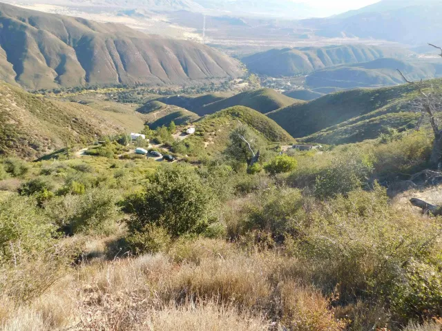 an aerial view of a house with a yard and mountain view in back