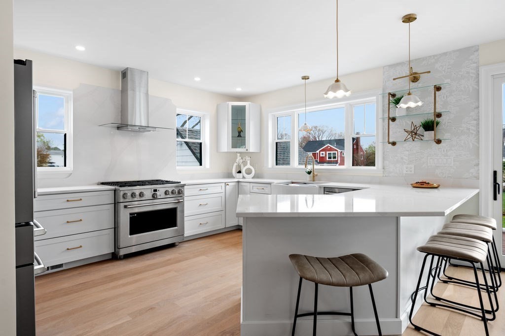 a kitchen with stainless steel appliances a stove a sink dishwasher and a refrigerator with wooden floor