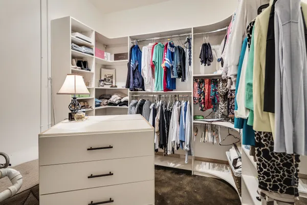 a view of walk in closet with clothes and shoes