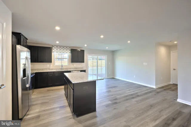 a large kitchen with kitchen island a sink dishwasher stove and oven with wooden floor