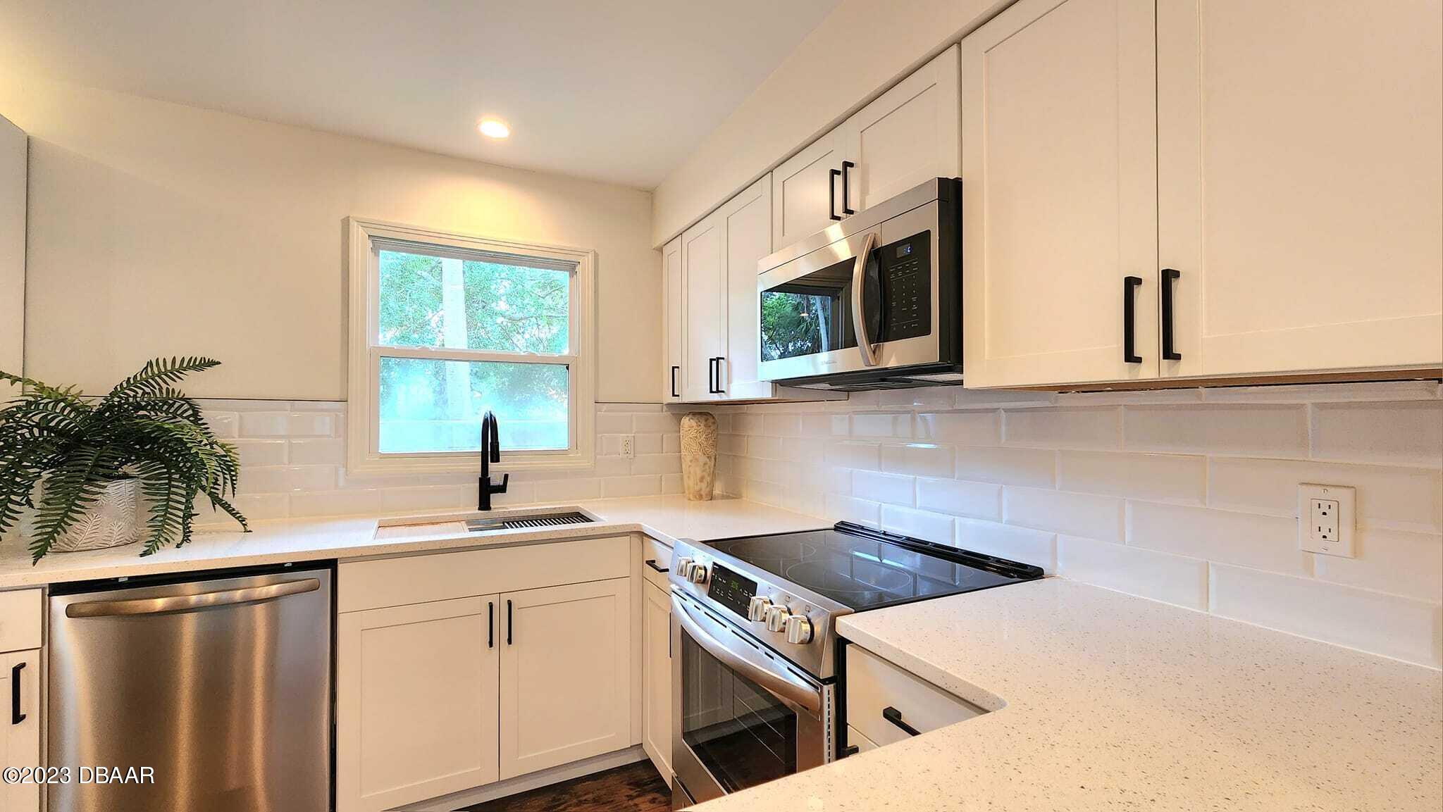 912 North Halifax Drive Ormond Beach, FL 32176 - Photo 38 of 65 a kitchen with stainless steel appliances a sink a stove a microwave and cabinets