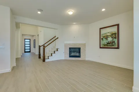 a view of an empty room with wooden floor and a fireplace