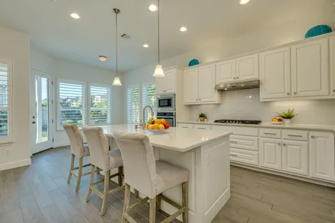 a kitchen with stainless steel appliances white cabinets and wooden floor