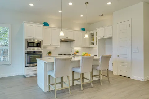 a kitchen with stainless steel appliances kitchen island granite countertop a table chairs sink and cabinets