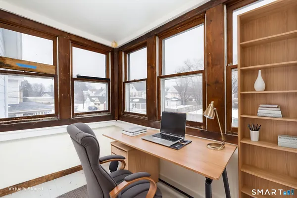 a view of a workspace with furniture and a window