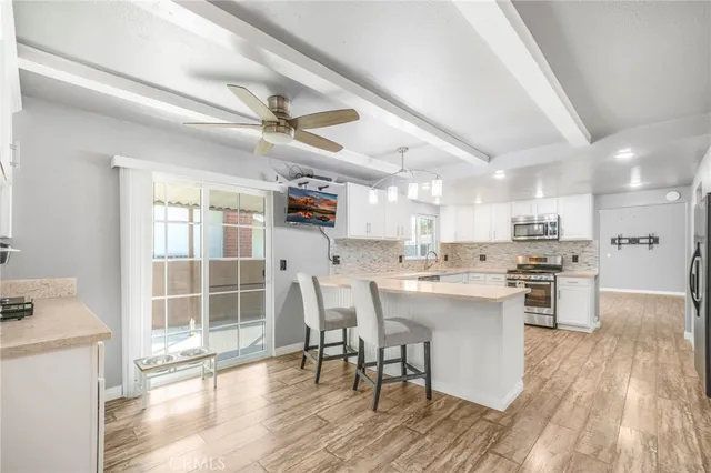 a kitchen with stainless steel appliances a dining table chairs stove refrigerator and cabinets