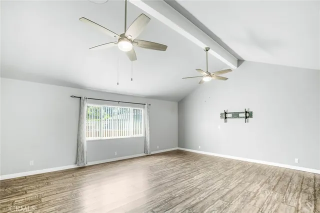 an empty room with wooden floor chandelier fan and windows