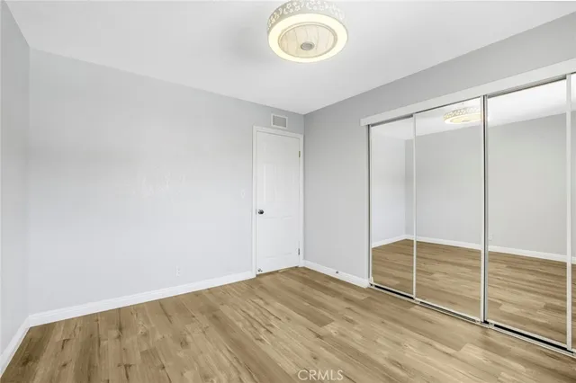 an empty room with wooden floor and mirror