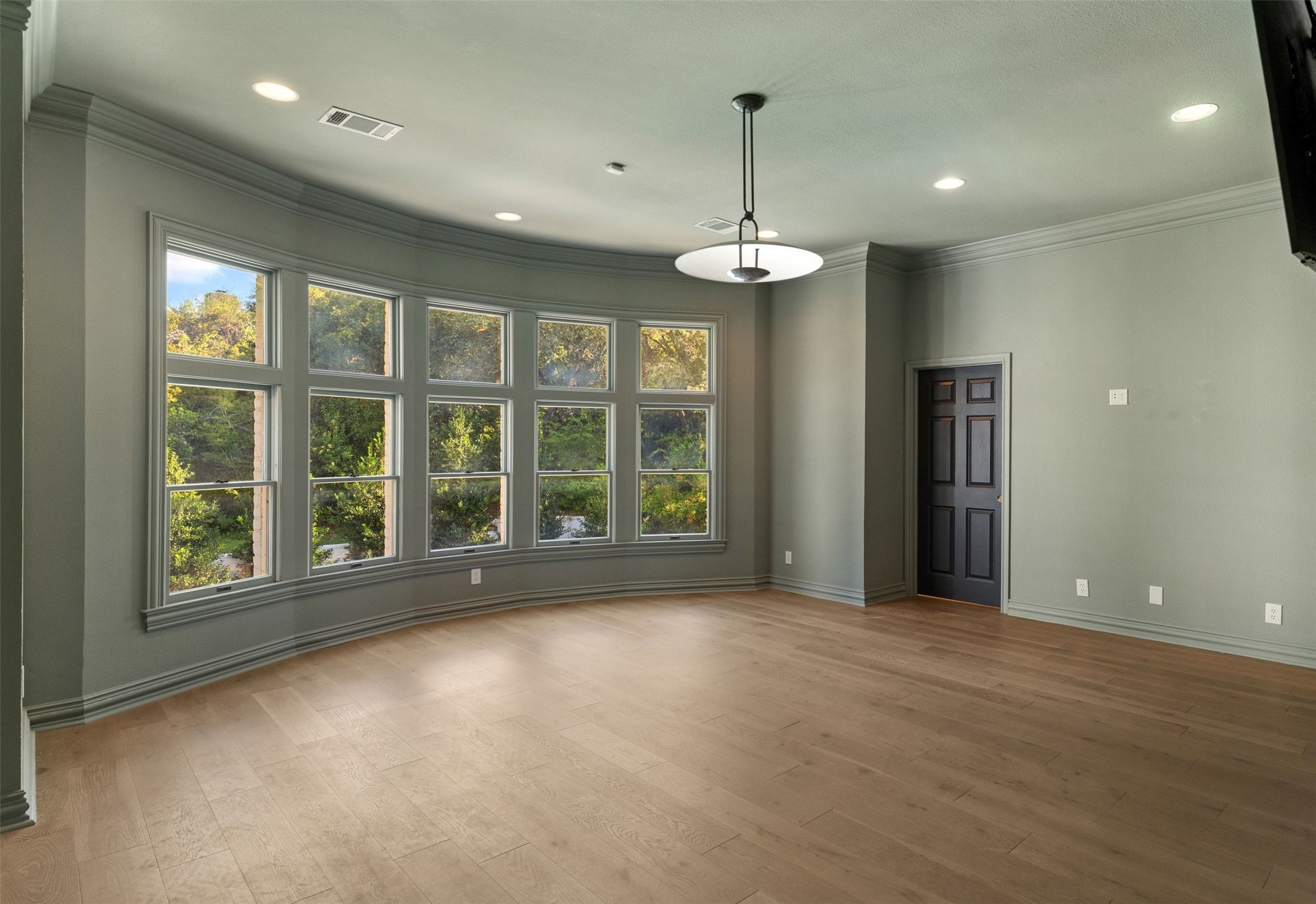 4201 Green Cliffs Road Austin, TX 78746 - Photo 26 of 40 A curved wall of windows frames tree-lined views in this spacious upstairs game room, ideal for movie nights, play space, or a home gym setup